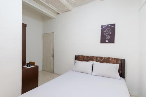 ein weißes Schlafzimmer mit einem Bett und einer Tafel an der Wand in der Unterkunft OYO Life 2108 Griya Aisyah Residence in Surabaya