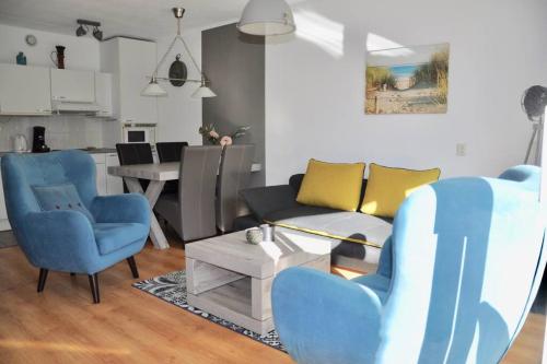 a living room with blue chairs and a couch at Appartement Badhotel 301 in Callantsoog