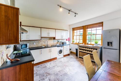 cocina con armarios blancos y mesa de madera en Garden Flat West Kincaple House, en St Andrews