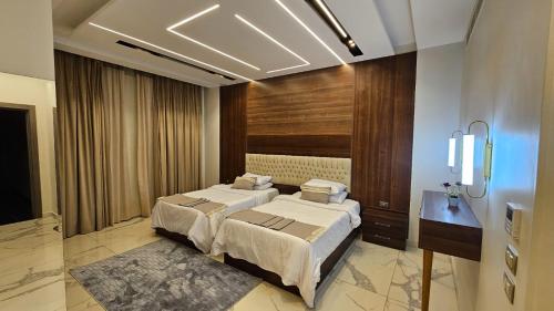 a bedroom with two beds and a table in it at My Villa Hotel in Sheikh Zayed