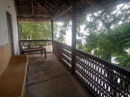 a screened in porch with a bench and trees at Seafront House in Lamu