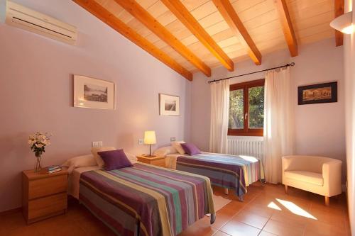 a bedroom with two beds and a chair and a window at La Salve dalt in Pollença