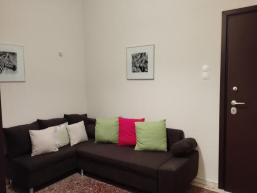 um sofá preto com almofadas coloridas numa sala de estar em Krokida Unique Apt em Corinto