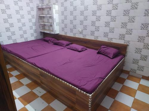 Cama en habitación con sábanas y almohadas moradas en Annu Bhai sewa sadan en Mathura