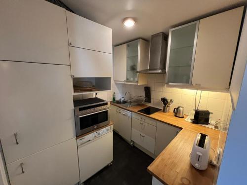 eine Küche mit weißen Schränken und einer hölzernen Arbeitsplatte in der Unterkunft Appartement calme à Bercy non loin de l'Accor Aréna in Paris