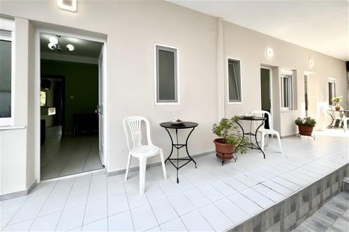 a patio with white chairs and a table and tables at Eleftheria Apartments Polychrono in Polychrono