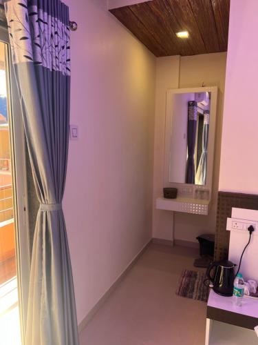 a room with a curtain and a mirror at Hotel Mahabaleshwar Mount View in Mahabaleshwar