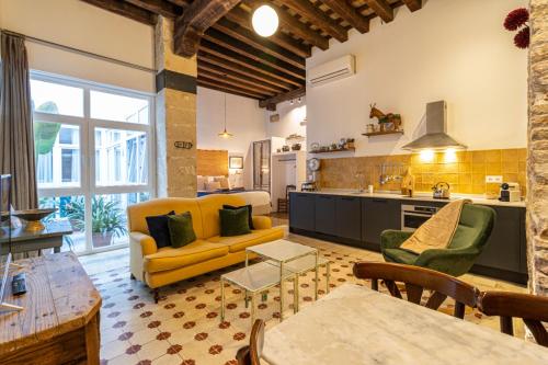 a living room with a yellow couch and a kitchen at Entre Bodegas Jerez in Jerez de la Frontera