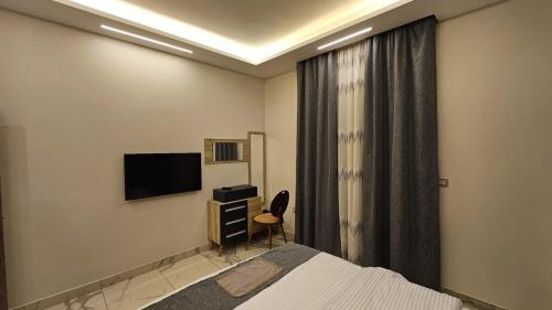 a bedroom with a bed and a desk and a television at My Villa Hotel in Sheikh Zayed