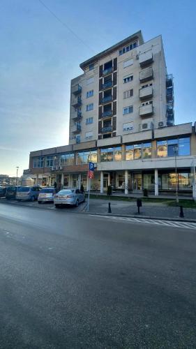 Un gran edificio con coches aparcados delante. en Negotin Centar Apartman II, en Negotin