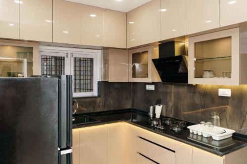 a kitchen with white cabinets and black counter tops at Williams Park Suite in Bangalore