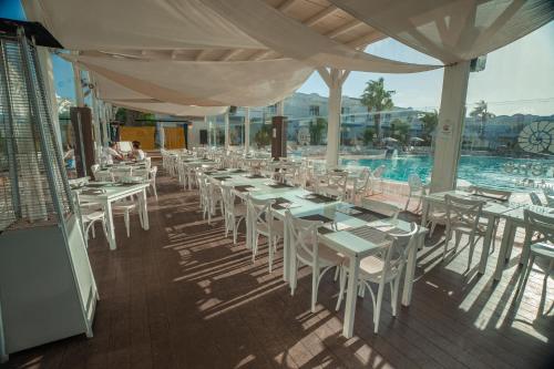 a restaurant with white tables and chairs and a swimming pool at Hotel Arena Beach in Corralejo