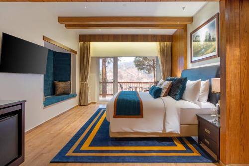 a bedroom with a large bed and a television at Moksha Himalaya Spa Resort in Kasauli