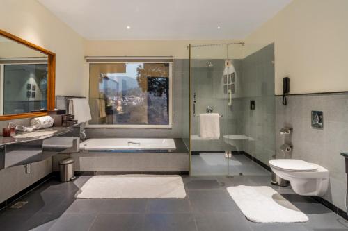 a bathroom with a tub and a sink and a toilet at Moksha Himalaya Spa Resort in Kasauli