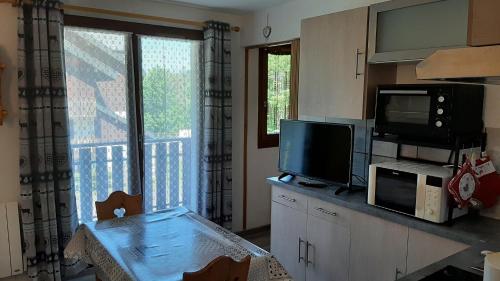 Il comprend une cuisine avec une table, une télévision et une fenêtre. dans l'établissement Bernex T2 toute saison au pied des pistes, à Bernex