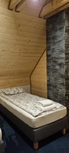 a bed in a room with a wooden wall at Domek ASPEN in Wetlina