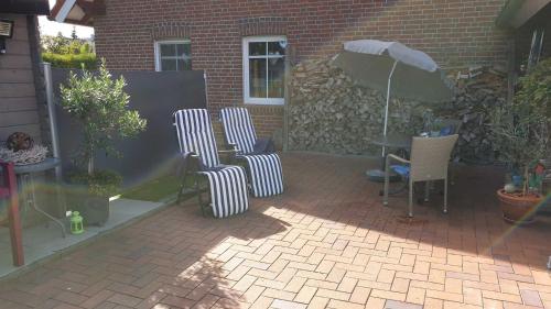 une terrasse avec 3 chaises et une table avec un parasol dans l'établissement Ferienwohnung Zum Lotsen, 45227, à Jemgum