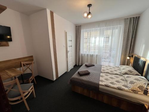 a bedroom with a bed and a chair and a window at Willa Dorota in Krynica Zdrój