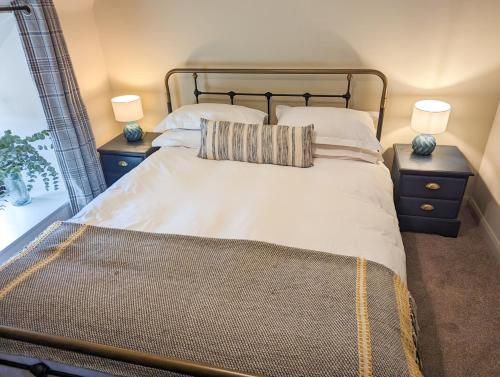 1 dormitorio con 1 cama grande y 2 mesitas de noche en Lindisfarne Cottage, en Beadnell