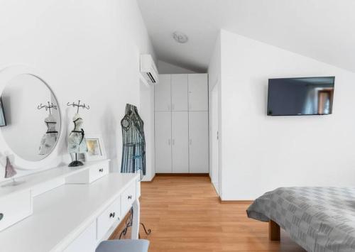 a white bedroom with a bed and a mirror at Villa Vesna with tennis court in Pićan