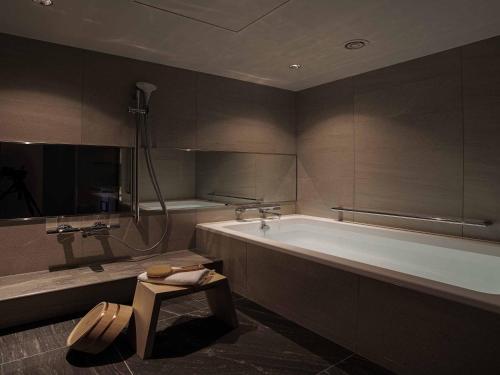 ein großes Bad mit einer Badewanne und einem Tisch in der Unterkunft Nagoya Kanko Hotel in Nagoya