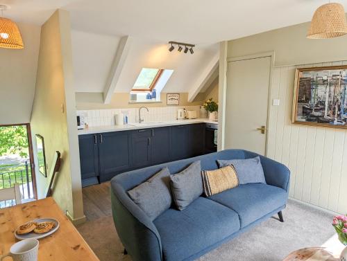 ein Wohnzimmer mit einem blauen Sofa und einer Küche in der Unterkunft The Hayloft in Beadnell