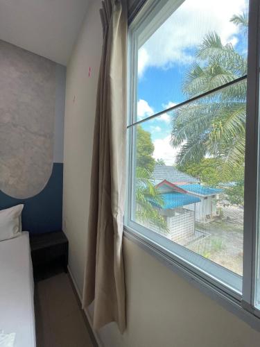 a bedroom with a window with a view of a palm tree at MR Homestay HotelStyle Room Teluk Intan in Teluk Intan