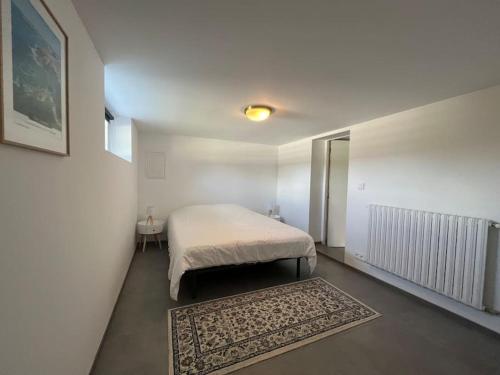 a white bedroom with a bed and a rug at Appartement Vannes avec jardin in Saint-Avé