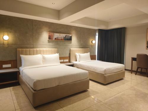 a hotel room with two beds and a couch at Hotel Le Opera in Bengaluru
