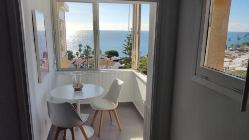 Loft La Cala de Mijas beach estudio mirando al mar في لا كالا ذي ميخاس: طاولة بيضاء وكراسي في غرفة مع نافذة
