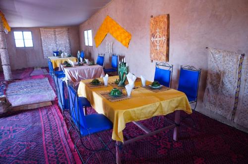 a room with two tables and blue chairs in it at Erg Chegaga Lodge in Mhamid