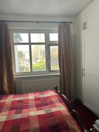 a bedroom with a bed with a plaid blanket and a window at Greenwich house in London