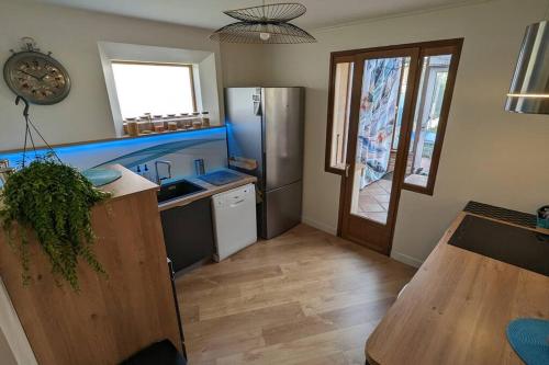 une cuisine avec un réfrigérateur en acier inoxydable et une table dans l'établissement Maison Cormeilles-en-Parisis, à Cormeilles-en-Parisis