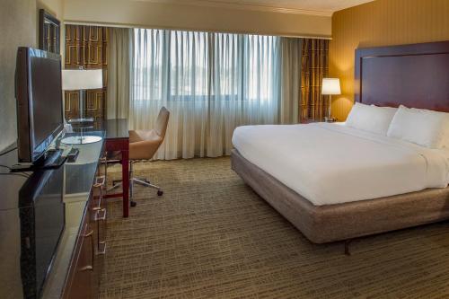 a hotel room with a bed and a desk and a television at Crowne Plaza Hotel St. Louis Airport by IHG in Bridgeton