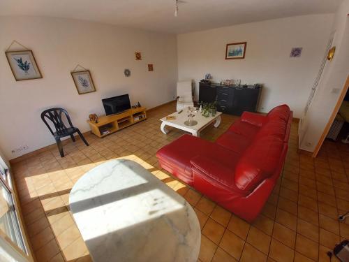 ein Wohnzimmer mit einem roten Sofa und einem Tisch in der Unterkunft Le Temps d'une Pause au Calme in Bouaye