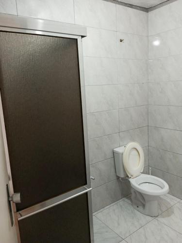 La salle de bains est pourvue de toilettes et d'une porte de douche. dans l'établissement Quarto próximo ao shopping Moinhos, à Porto Alegre