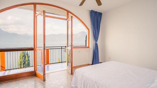 een slaapkamer met een bed en een groot raam bij Villa Mirella - Italian Homing in Torri del Benaco