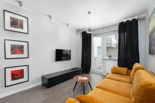 een woonkamer met een bank en een tv bij Raginisa Modern Apartments in Szczecin