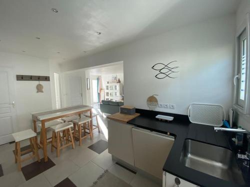 une cuisine avec comptoirs noirs, table et chaises dans l'établissement La Contis spa, à Saint-Julien-en-Born