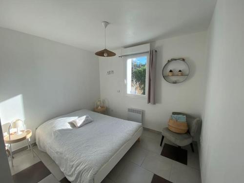 a white bedroom with a bed and a window at La Contis spa in Saint-Julien-en-Born
