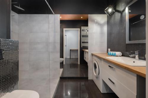 a bathroom with a sink and a washing machine at Raginisa Modern Apartments in Szczecin