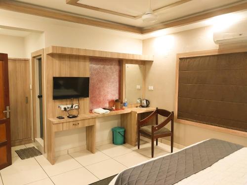 a hotel room with a desk with a television and a bed at Hotel Royal Wings in Elūr