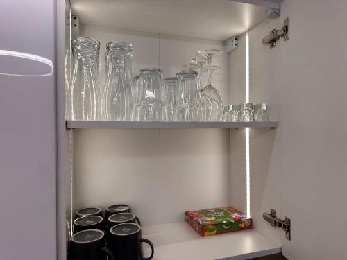 a cupboard with glasses on top of it with a shelf at Aparthotel Zabrze, Apartament Agnieszka in Zabrze
