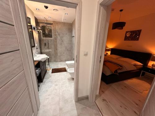 ein Schlafzimmer mit einem Bett und ein Badezimmer mit einem Waschbecken in der Unterkunft Aparthotel Zabrze, Apartament Agnieszka in Zabrze