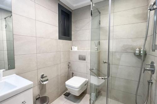 a bathroom with a toilet and a glass shower at 1BHK Near Airport, Pool, Parking in Muscat