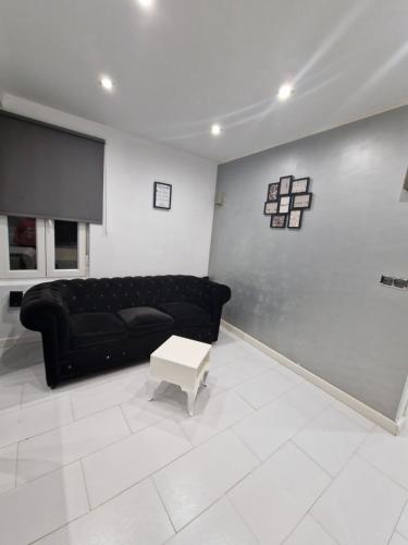 sala de estar con sofá negro y mesa en La casita de Antonella - centro de Comillas, en Comillas