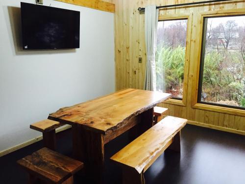 een houten tafel en banken in een kamer met een raam bij Cabañas Alto Cordillera in Las Trancas