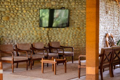 a waiting room with chairs and a tv on a wall at Sanctuary Chitwan National Park in Chitwan