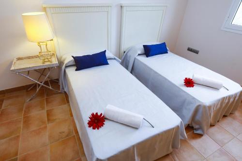 two beds in a room with red flowers on them at New Aiguesverdes ONLY FAMILIES in Reus