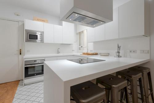 a white kitchen with a counter and stools at Spacious bright- 2Bd 2Bth- Recoletos in Madrid